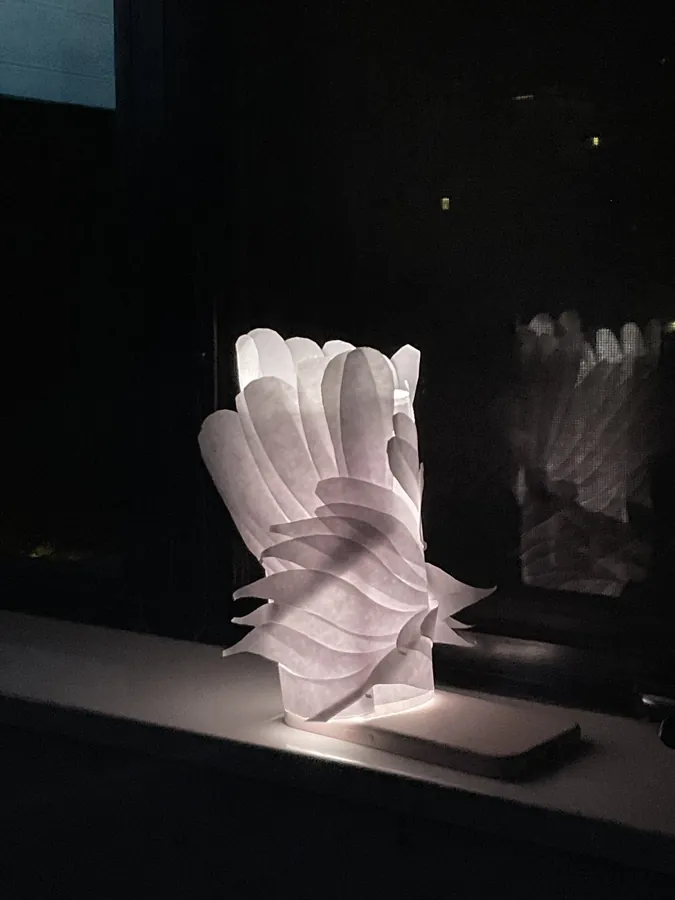 A lamp built from layered translucent paper petals, glowing on a windowsill at night.