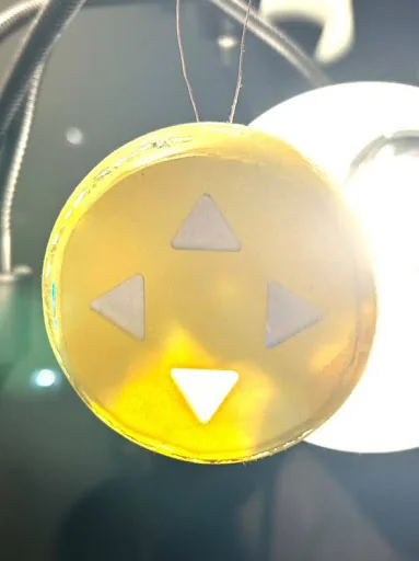 The finished translucent prototype glowing amber, hanging in a car with its downward arrow lit white.